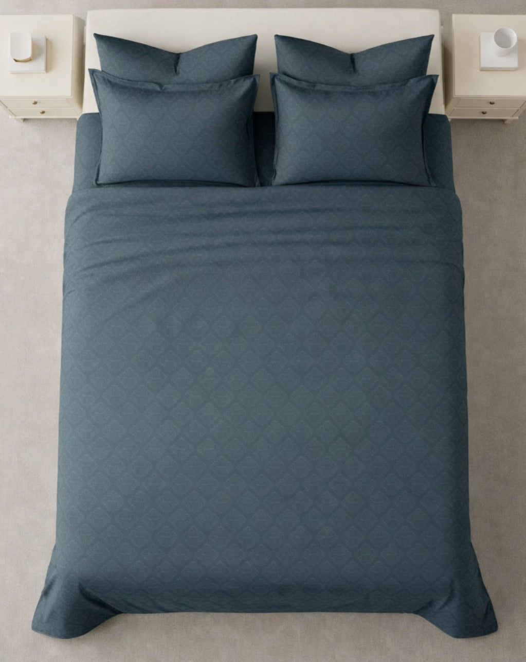 Blue quilted bedspread on a bed with matching pillows in a minimalistic bedroom setting.