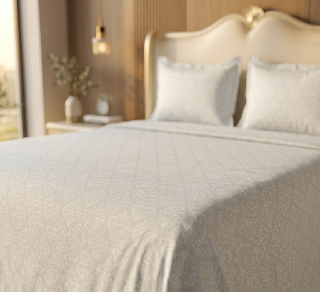 Neatly made bed with grey bedding and pillows in a bedroom setting.