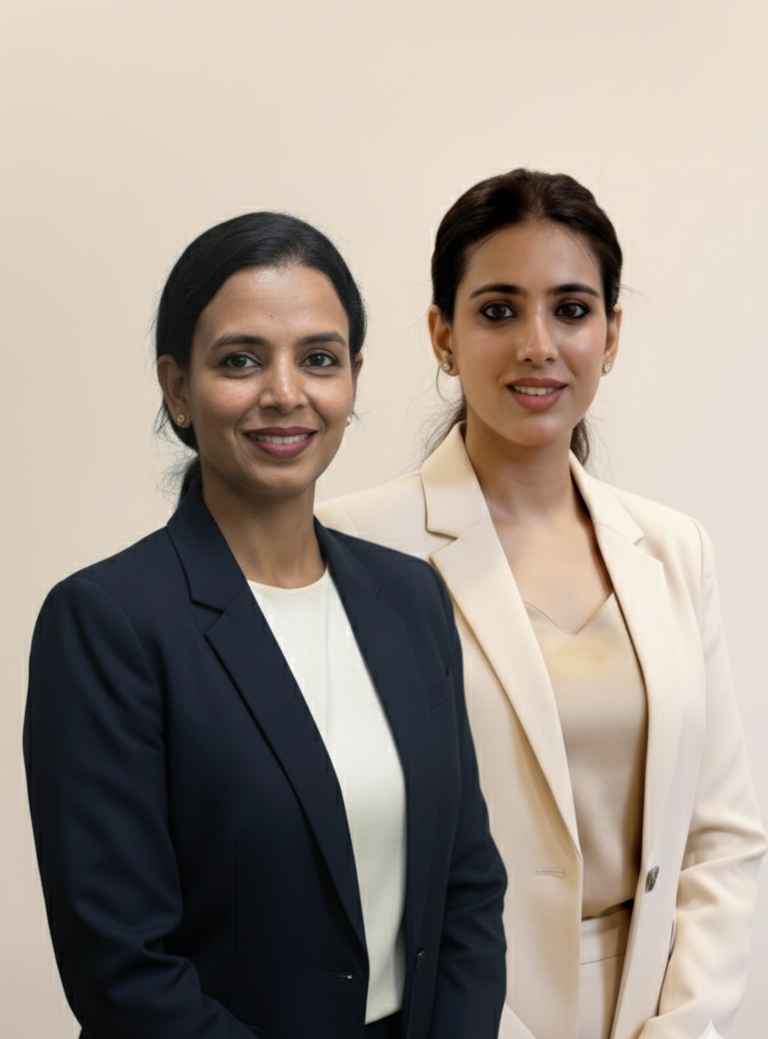 Two women in professional attire standing against a plain background